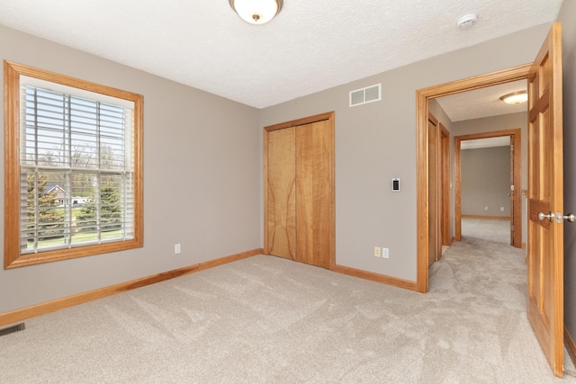 unfurnished bedroom with light colored carpet, a closet, visible vents, and baseboards