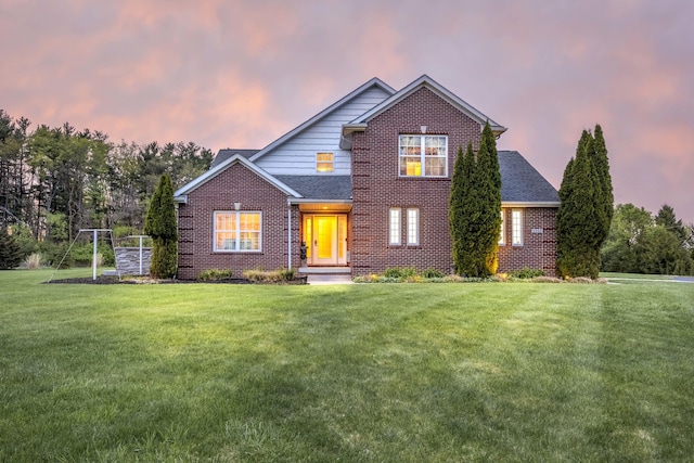 traditional-style house featuring a lawn, brick siding, and a shingled roof