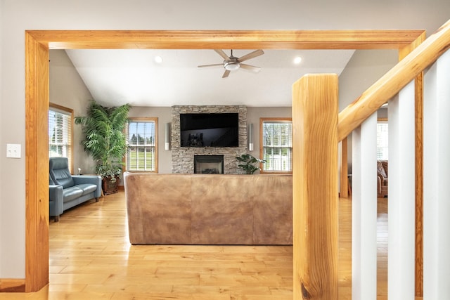 living room with a ceiling fan, lofted ceiling, a healthy amount of sunlight, wood finished floors, and a fireplace