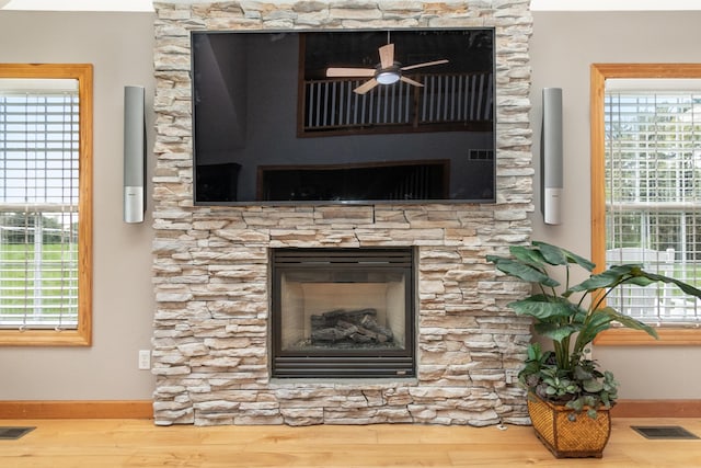 details featuring visible vents, a fireplace, ceiling fan, and wood finished floors