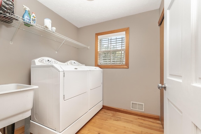laundry room with light wood finished floors, laundry area, visible vents, baseboards, and independent washer and dryer