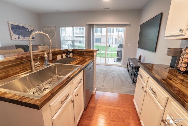 kitchen with dishwasher, butcher block counters, visible vents, a sink, and white cabinets
