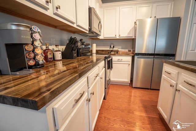 kitchen featuring light wood finished floors, wood counters, white cabinetry, and stainless steel appliances