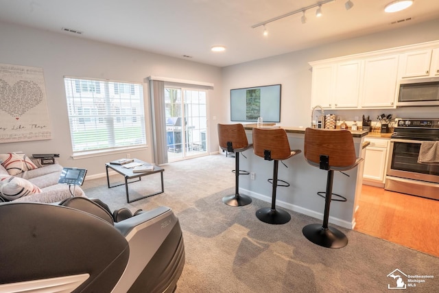 interior space with track lighting, visible vents, baseboards, and light carpet