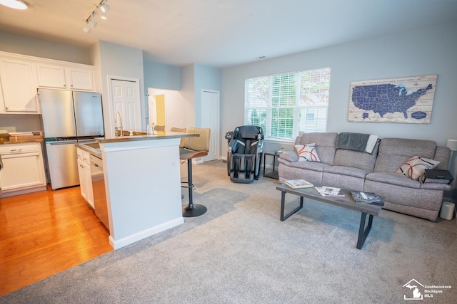 kitchen featuring freestanding refrigerator, rail lighting, open floor plan, and light colored carpet