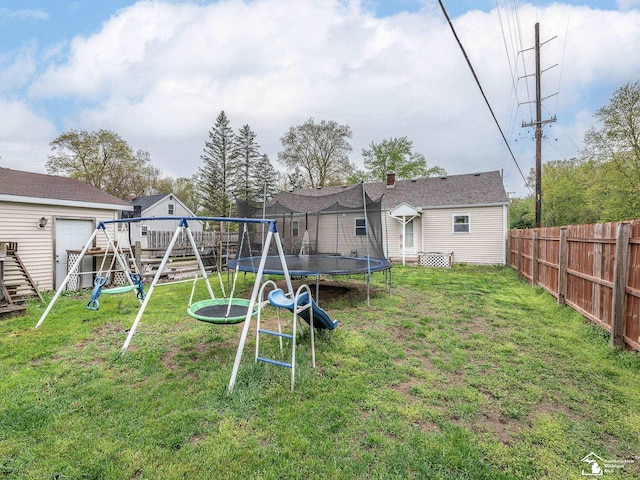 view of yard featuring a trampoline, a playground, and fence