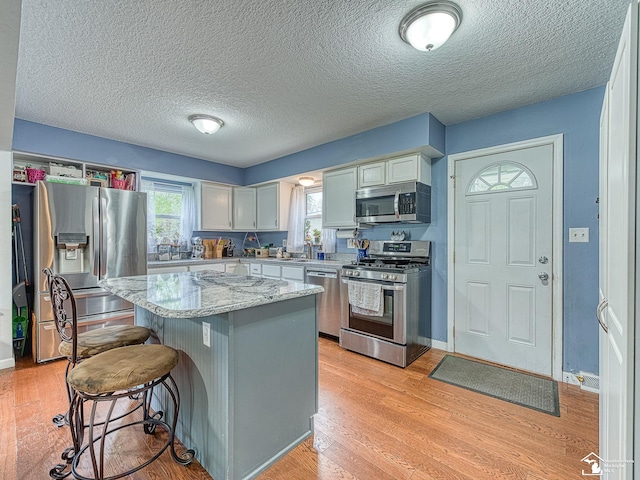 kitchen featuring a kitchen island, light wood-style floors, stainless steel appliances, and a kitchen breakfast bar