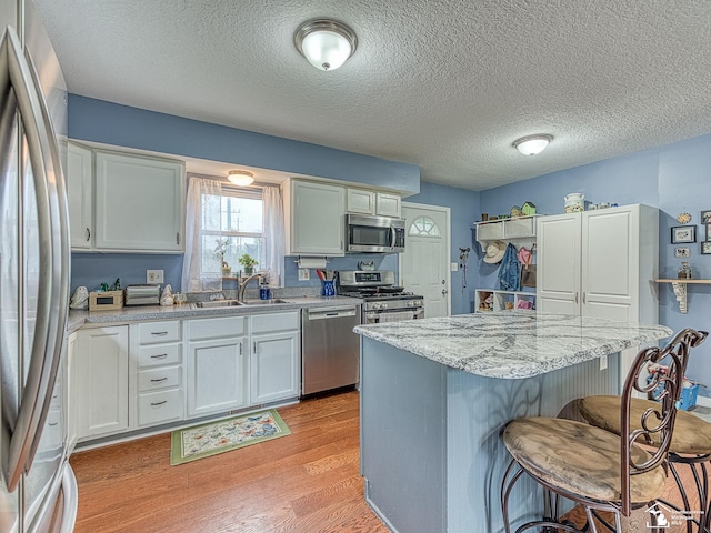 kitchen featuring a sink, appliances with stainless steel finishes, a breakfast bar area, a kitchen island, and light wood-style floors