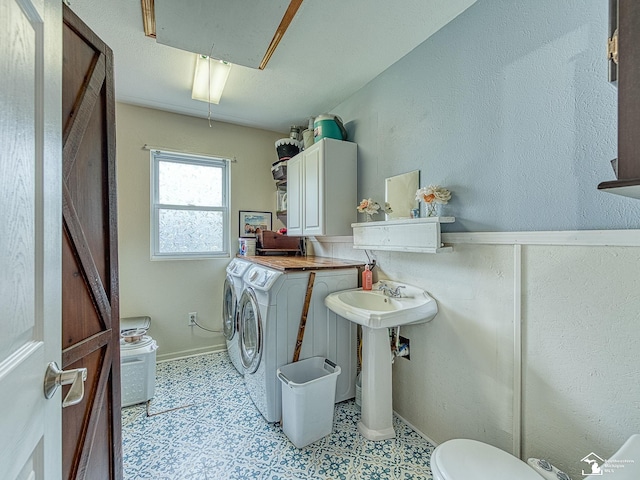 bathroom featuring tile patterned floors, washing machine and clothes dryer, toilet, and a sink