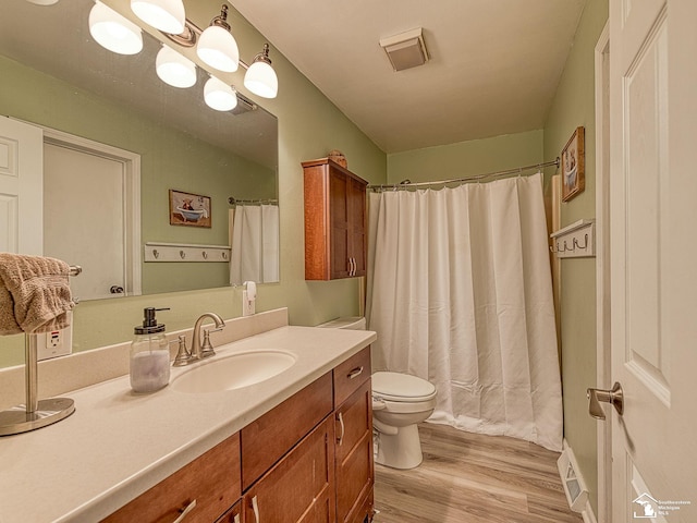 bathroom with toilet, wood finished floors, a shower with curtain, visible vents, and vanity