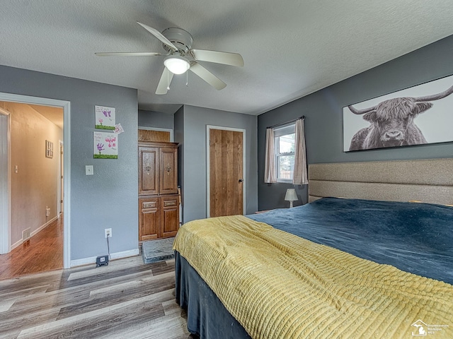 bedroom featuring wood finished floors, a closet, a textured ceiling, baseboards, and ceiling fan