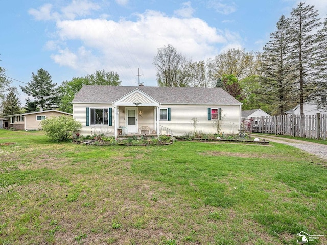 view of front facade with a front yard, covered porch, and fence