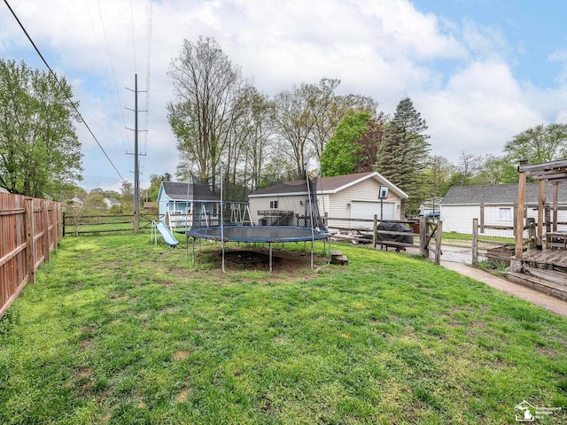 view of yard with a fenced backyard, an outbuilding, a detached garage, a trampoline, and a playground