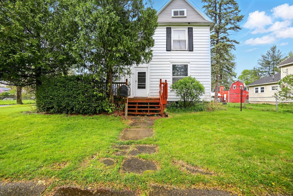 back of property with a yard, fence, and a wooden deck