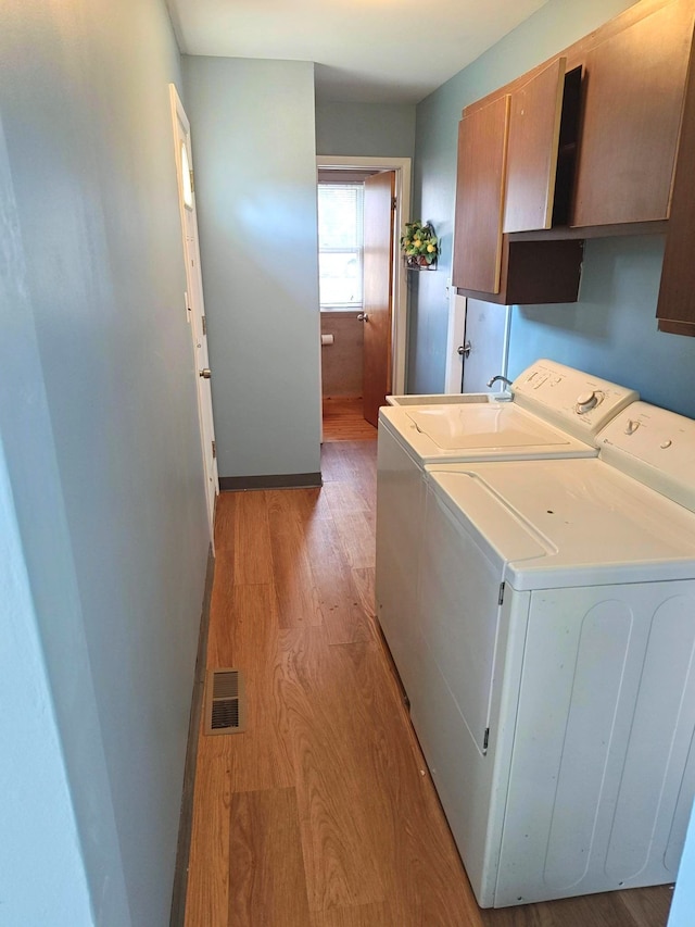 3385 Muerknoll Dr, Troy, MI 48084 - clothes washing area with cabinet space, washing machine and clothes dryer, light wood-style flooring, and baseboards