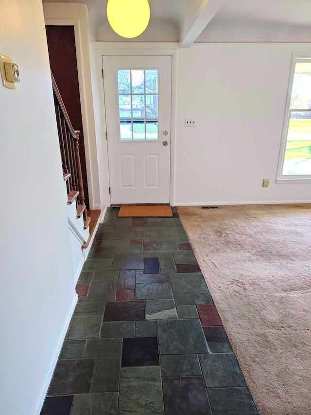 entryway with carpet, stone finish floor, stairway, baseboards, and visible vents