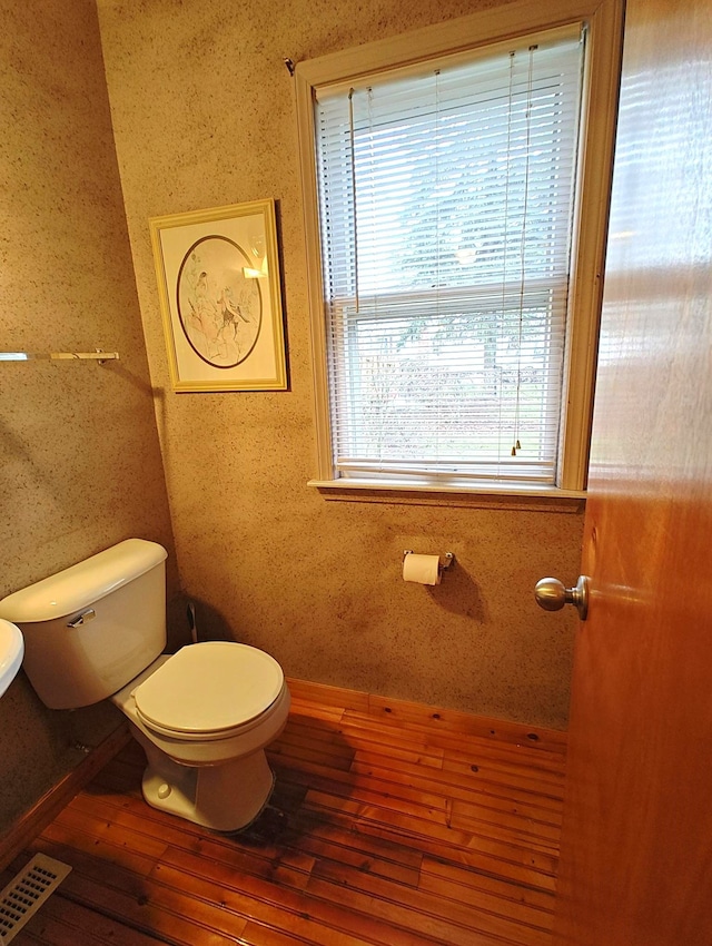 half bath featuring toilet, wood-type flooring, and baseboards