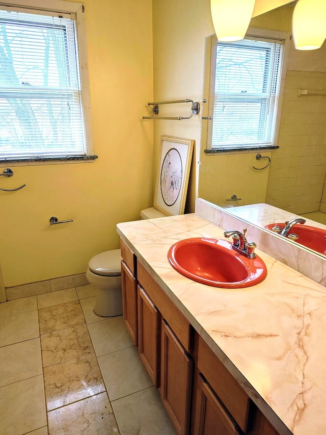 bathroom with toilet, a wealth of natural light, tile patterned floors, and vanity