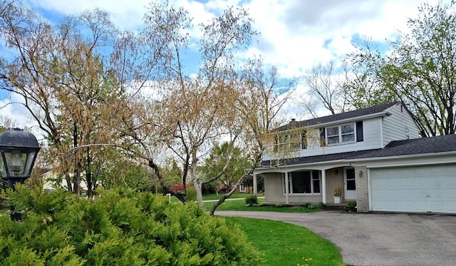 traditional home with driveway, roof with shingles, brick siding, and a garage