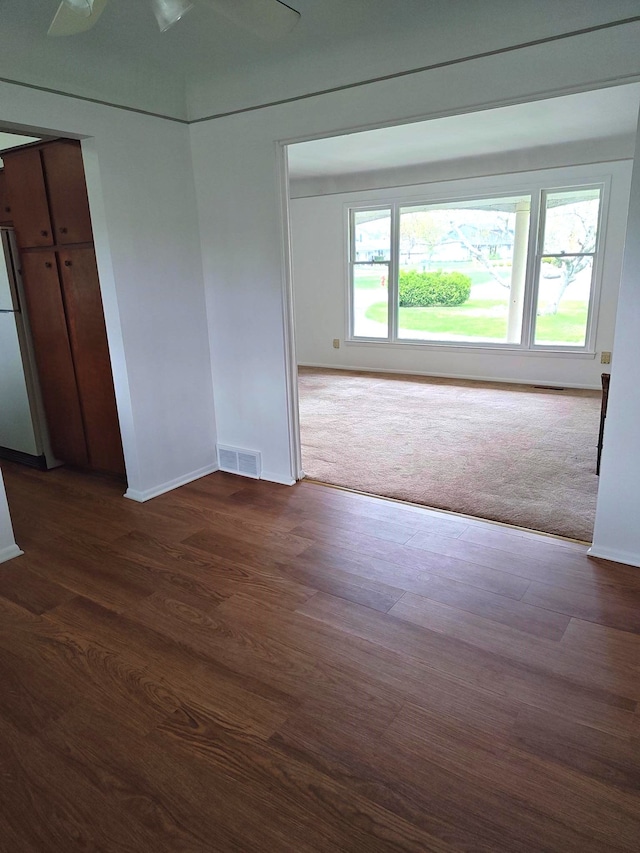 empty room with baseboards, visible vents, and dark wood finished floors
