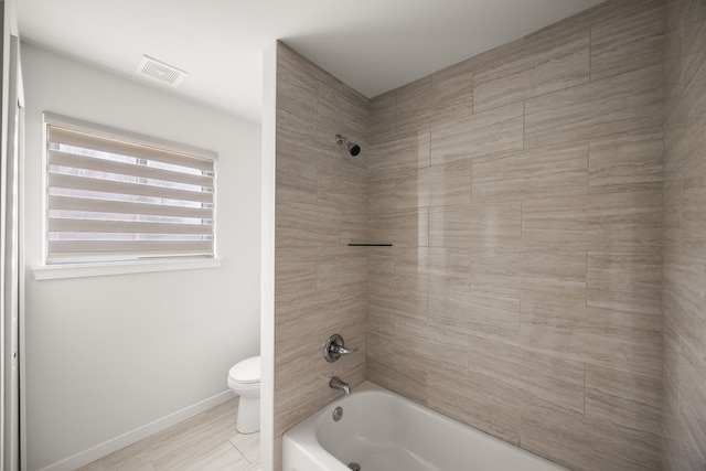 bathroom featuring toilet, baseboards, visible vents, and shower / washtub combination