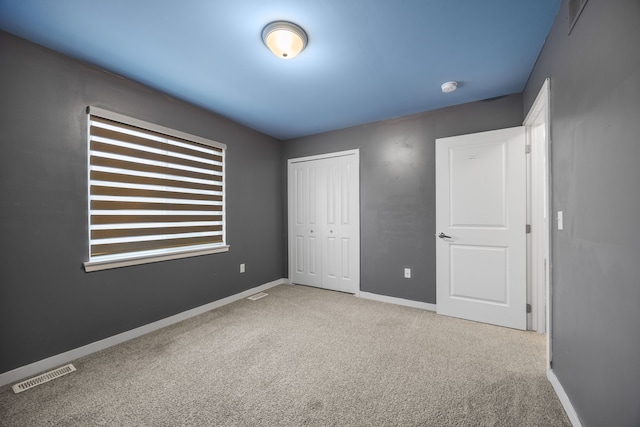 unfurnished bedroom with carpet flooring, baseboards, a closet, and visible vents
