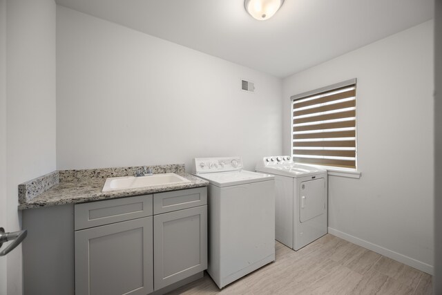 laundry room featuring a sink, light wood-type flooring, visible vents, baseboards, and independent washer and dryer