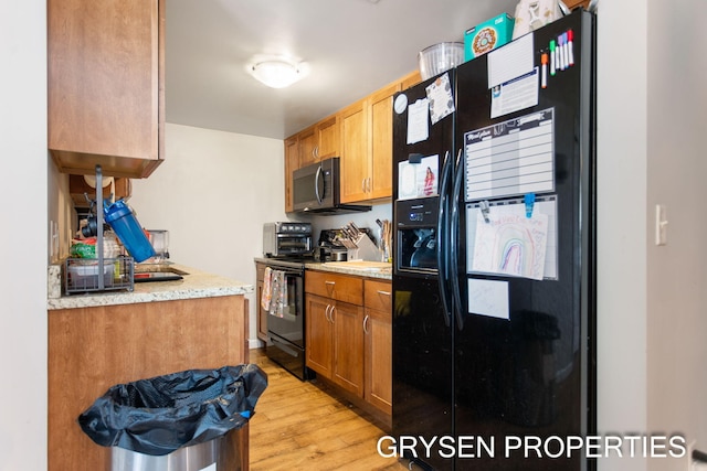 kitchen featuring brown cabinetry, black appliances, and light wood-style floors