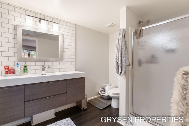 full bathroom featuring a stall shower, toilet, decorative backsplash, and wood finished floors
