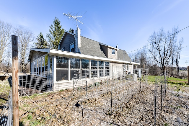 4780 Dutcher Rd, Howell, MI 48843 - back of property with a chimney, a gambrel roof, roof with shingles, and a sunroom