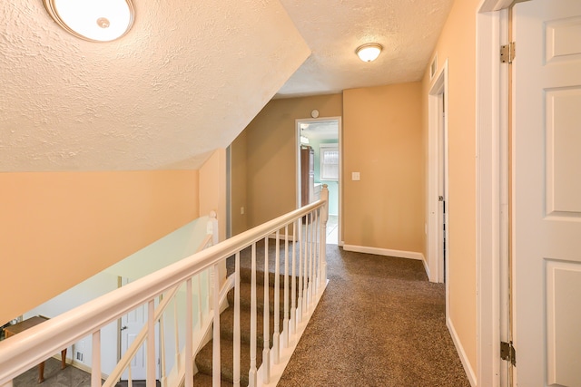 4780 Dutcher Rd, Howell, MI 48843 - hallway featuring a textured ceiling, baseboards, an upstairs landing, and dark carpet