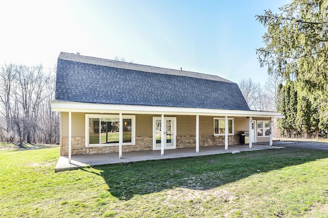 4780 Dutcher Rd, Howell, MI 48843 - back of property with stone siding, french doors, a gambrel roof, a yard, and roof with shingles