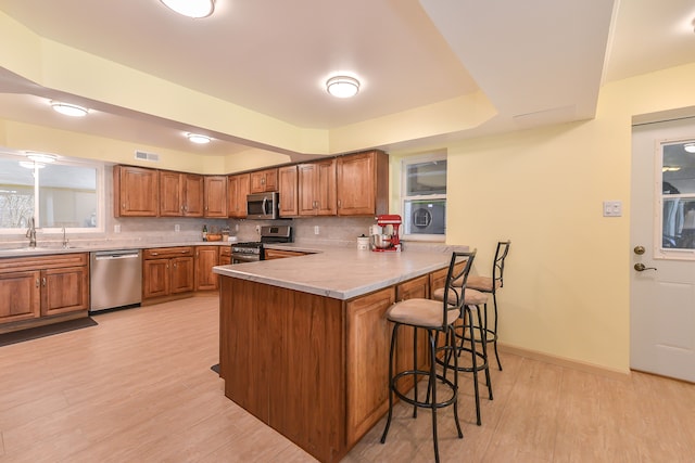 4780 Dutcher Rd, Howell, MI 48843 - kitchen with a peninsula, appliances with stainless steel finishes, brown cabinets, and a sink