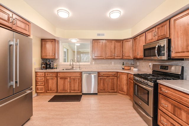 4780 Dutcher Rd, Howell, MI 48843 - kitchen with stainless steel appliances, brown cabinetry, visible vents, and a sink