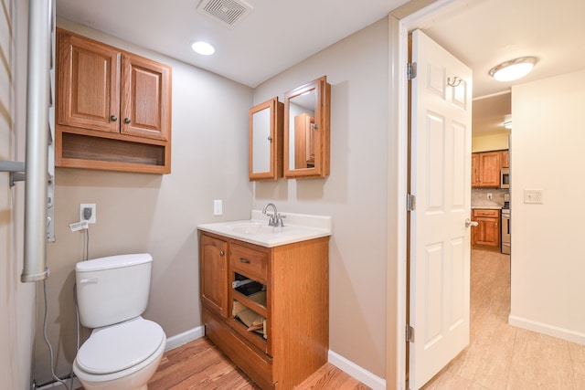 4780 Dutcher Rd, Howell, MI 48843 - bathroom featuring toilet, baseboards, visible vents, vanity, and wood finished floors