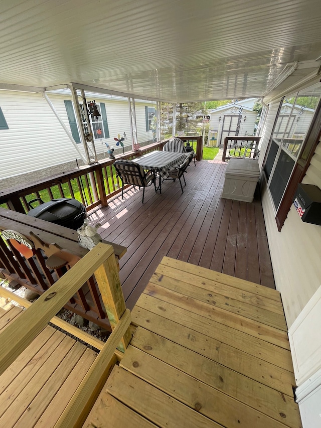 deck with outdoor dining area, a storage shed, and an outdoor structure