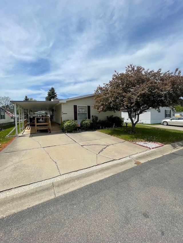 view of front facade featuring an attached carport, driveway, and a front yard