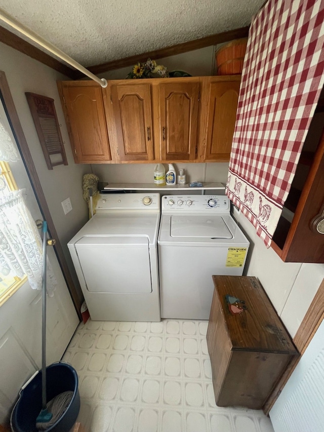washroom with washer and clothes dryer, cabinet space, light floors, and a textured ceiling