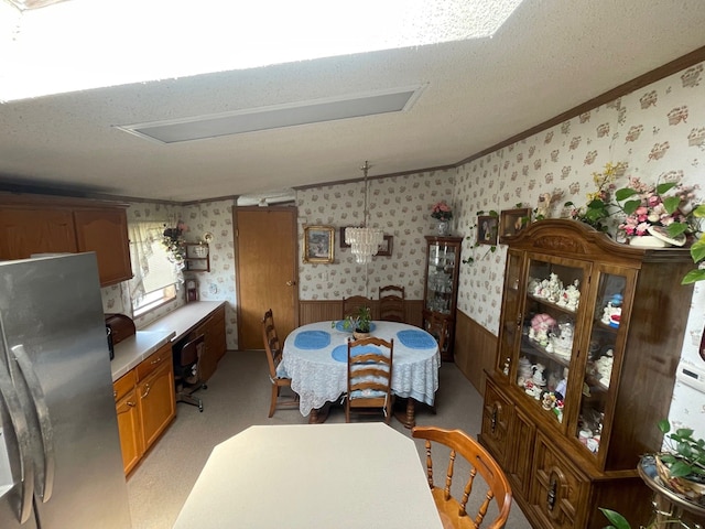 dining room with wallpapered walls, crown molding, wainscoting, and a textured ceiling