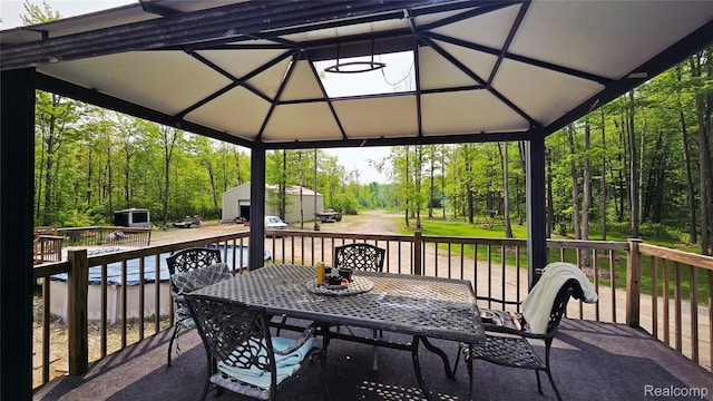 5303 Dove Rd, Kimball, MI 48074 - view of patio with outdoor dining space, a wooden deck, and a forest view