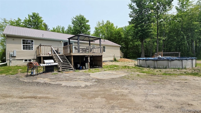 5303 Dove Rd, Kimball, MI 48074 - back of property featuring a deck, stairs, a covered pool, metal roof, and a gazebo