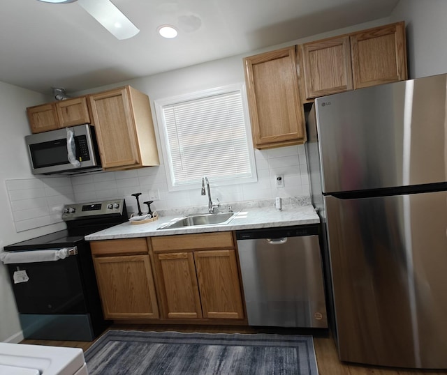 kitchen with a sink, stainless steel appliances, dark wood finished floors, backsplash, and light countertops