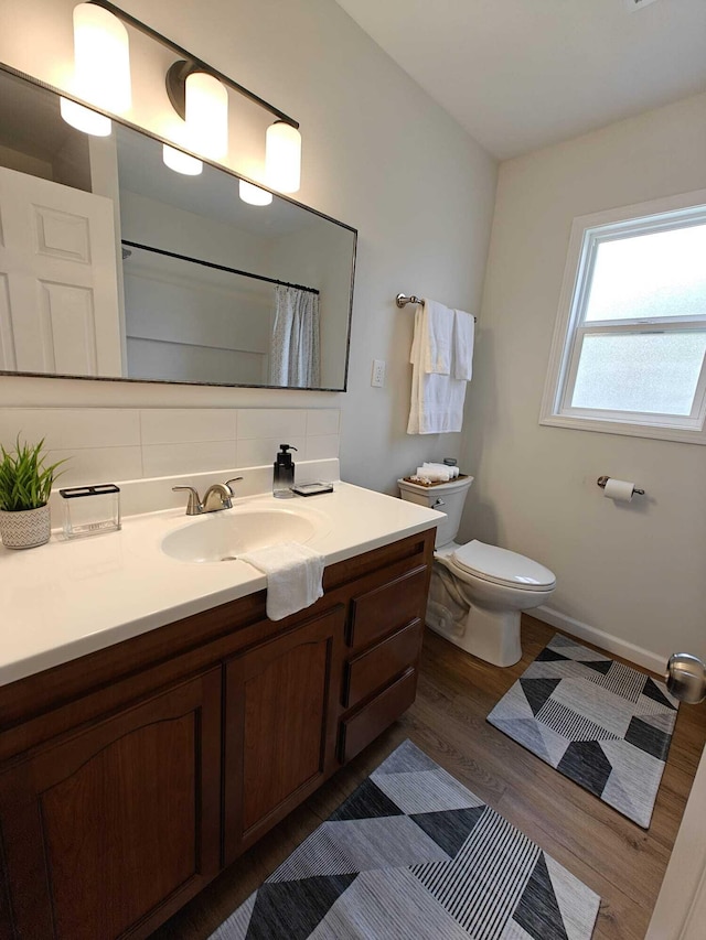 full bath with toilet, baseboards, vanity, decorative backsplash, and wood finished floors