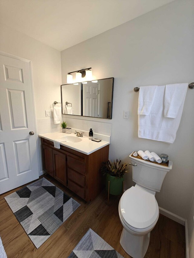 bathroom featuring toilet, vanity, decorative backsplash, and wood finished floors