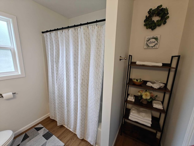full bath with toilet, a shower with shower curtain, wood finished floors, and baseboards