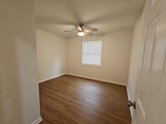 spare room with ceiling fan, baseboards, and dark wood-type flooring