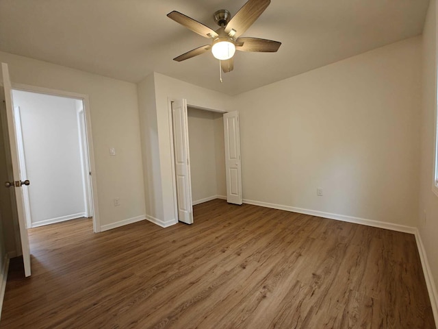 unfurnished bedroom featuring dark wood-style flooring, baseboards, a closet, and a ceiling fan