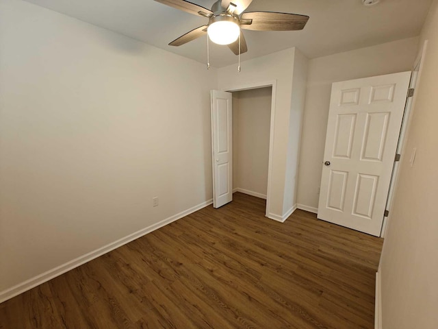 unfurnished bedroom with ceiling fan, baseboards, and dark wood-type flooring