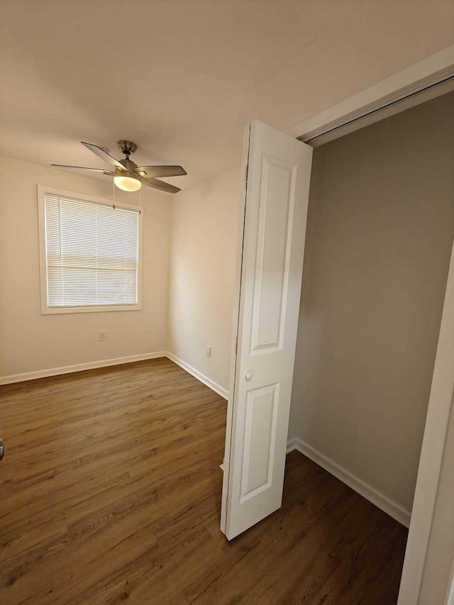 interior space featuring baseboards, a ceiling fan, and dark wood-style floors