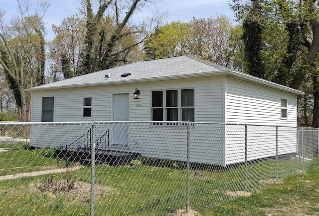 view of front of house with roof with shingles, fence, and a front yard